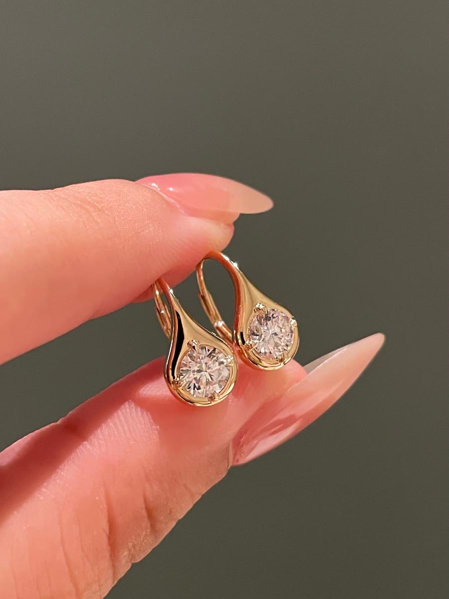 A finished pair of gold drop earrings set with round stones